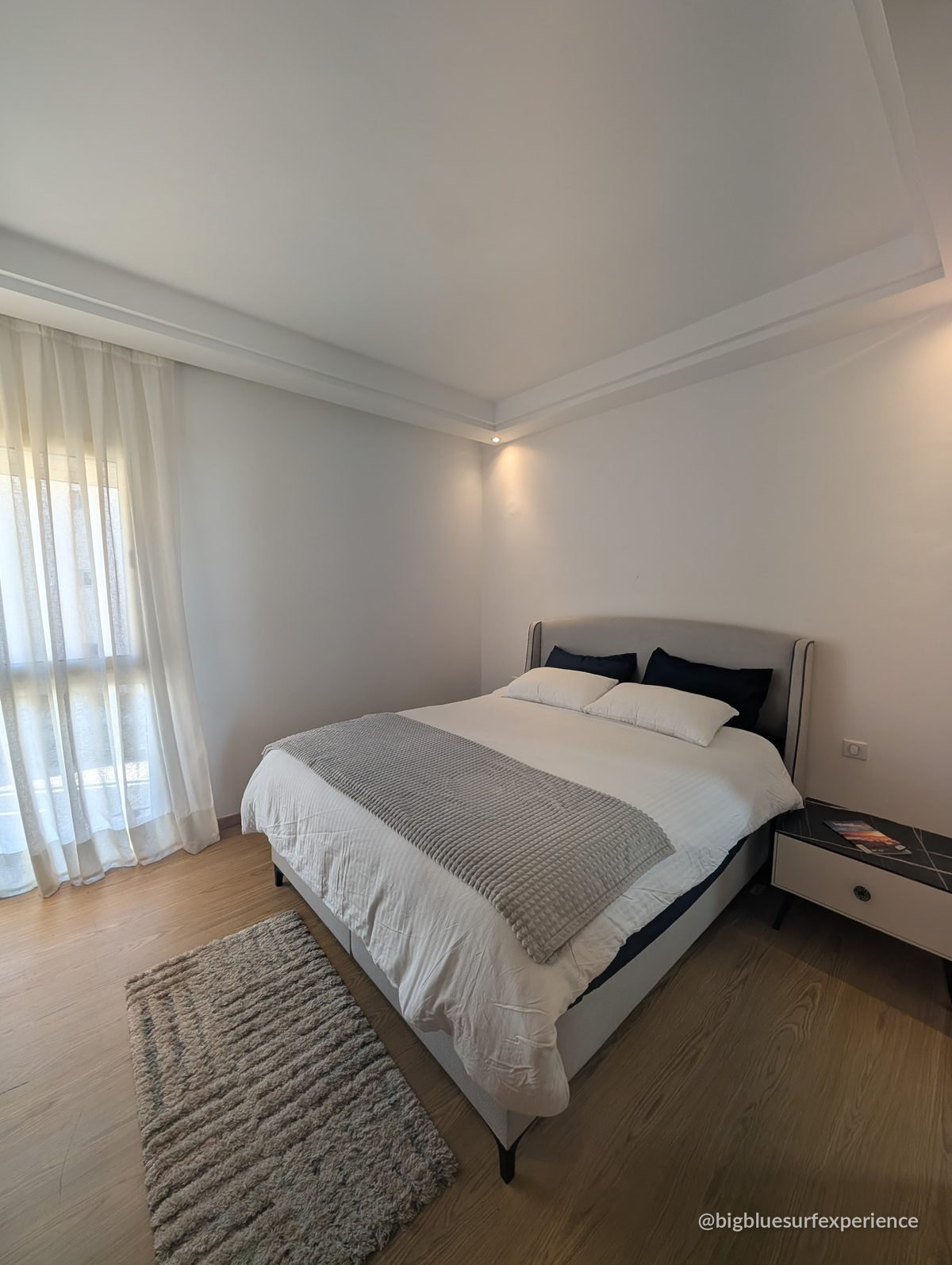 Master bedroom of the BigBlue Bay Studio with a double bed and wooden flooring