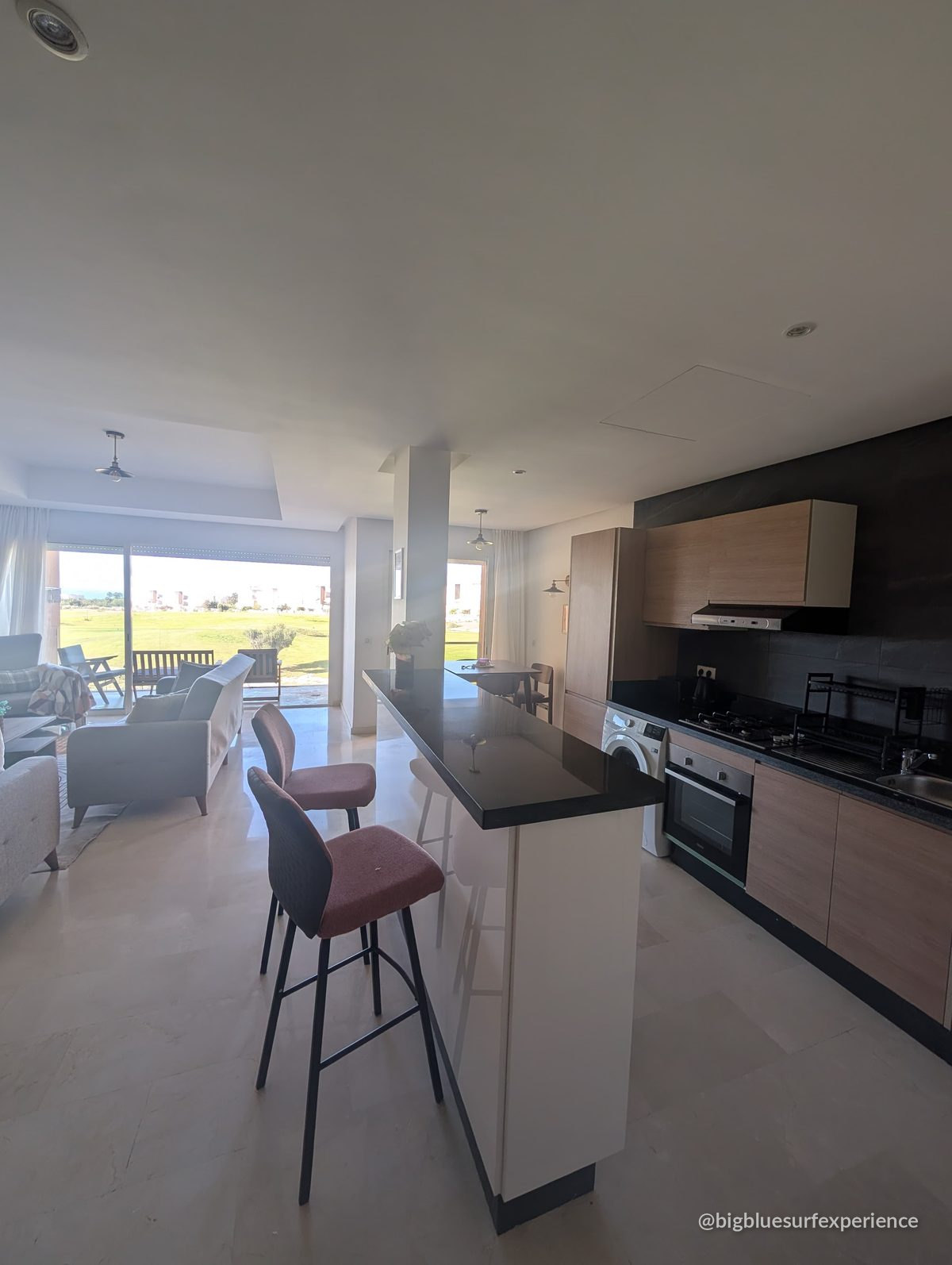 Open-plan kitchen, breakfast bar and living room of the BigBlue Bay Studio, with the balcony at the far end